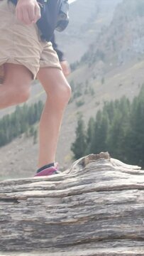 A child balances on a fallen tree by a mountain lake in a U.S. national park. Close-up of legs and boots Adventure, growth, childhood nature connection, eco-education Overcoming challenges and growing