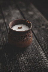 Candle in a brown clay pot on a wooden background