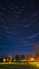 Night image with startrails and autumnal foliage on trees