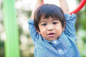 Little 2 - 3 year asian boy climbing on bar in outdoor playground city park