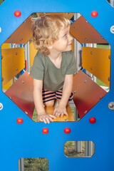 A little boy inside a climbing frame on a playground