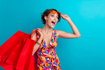 Photo of ecstatic woman with bob hairdo dressed colorful clothes hold new outfit staring empty...