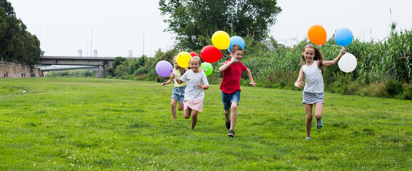 Children with balloons run in the summer park