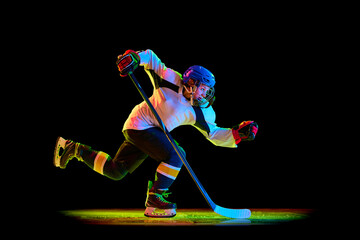 Competitive young woman, hockey player in motion, sliding on skates with pluck, training against...