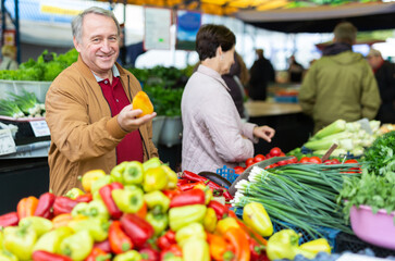 Mature married couple in casual clothes choosing organic bell peppers during date at local grocery market