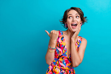 Fototapeta premium Photo of overjoyed funny woman dressed colorful clothes indicating look at sale promo empty space isolated on blue color background