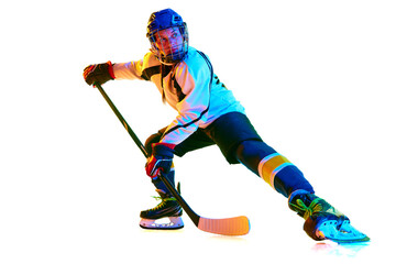 Motivation to win. Young girl, hockey player in helmet and uniform, training, playing against white background in neon light. Concept of professional sport, competition, game, action, hobby