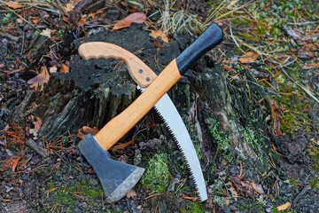 new modern dangerous   small  iron sharp with wooden handles hand hatchet  and wood saw lie on a...