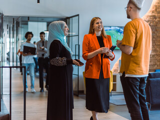 A group of young business colleagues, including a woman in a hijab, stands united in the modern corridor of a spacious startup coworking center, representing diversity and collaborative spirit