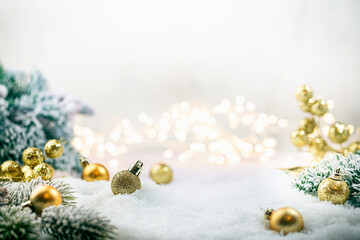 Christmas gold decorations on snow with fir tree branches and christmas lights. Winter Decoration Background - obrazy, fototapety, plakaty