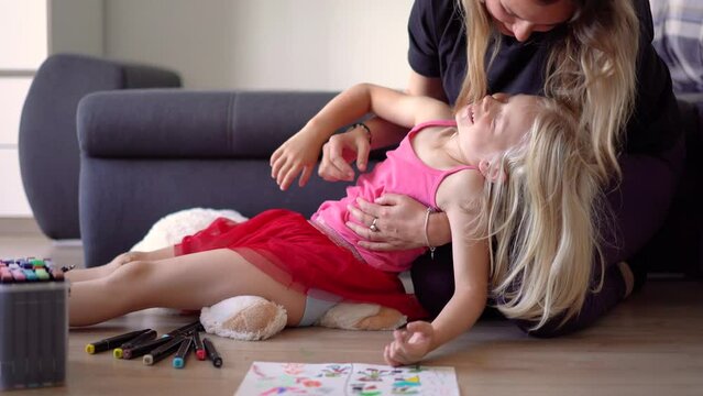 Little girl with her mother is painting on the floor at home