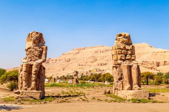 Famous  Colossi of Memnon - massive ruined statues of the Pharaoh Amenhotep III. Travel and tourist landmarks. Luxor, Egypt - October 21, 2023.