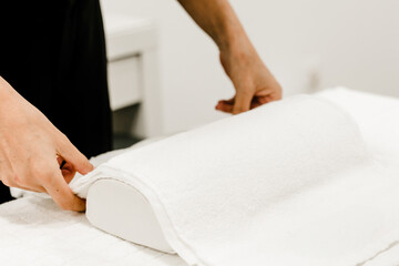 Close-up of a woman's hands arranging a towel on a table, preparing for a manicure session, highlighting meticulous setup.