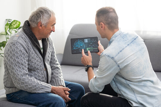 Picture Of European Doctor Talking With Elderly Male Patient And Sitting In The Studio, Isolated On White Background