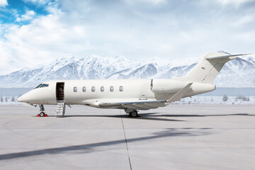 Modern white private jet with an opened gangway door at the winter airport apron on the background of high scenic snow capped mountains - obrazy, fototapety, plakaty
