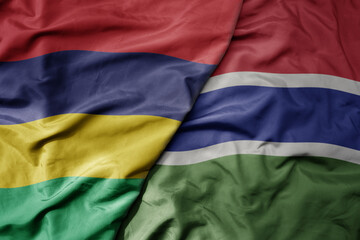 big waving national colorful flag of mauritius and national flag of gambia .