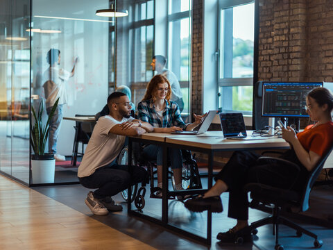 A diverse group of young business individuals congregates in a modern startup coworking center, embodying collaborative innovation and a dynamic atmosphere