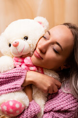Woman sitting on sofa with teddy bear. Retro photo with plush toy