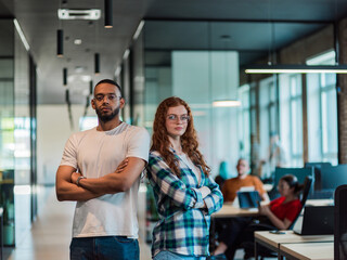 African-American businessman and his businesswoman colleague stand at the forefront with crossed arms, exuding confidence and leadership, while their diverse team diligently works behind them