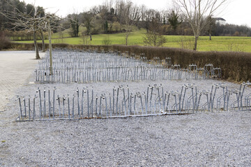 Large empty bicycle parking lot, parking space on gravel, trees without leaves during the day with cloudy skies, without people