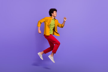 Full length profile side photo of cheerful glad man in trendy clothes going fast looking empty space isolated on purple color background