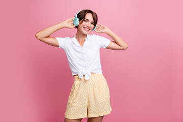 Obraz na płótnie Canvas Photo of good mood girl with bob hairstyle dressed white shirt touching headphones listen playlist isolated on pink color background