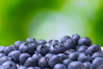 Close-up of juicy, ripe blueberries on a green blurred background. Beautiful bright background with berries, macro. Concept of healthy eating