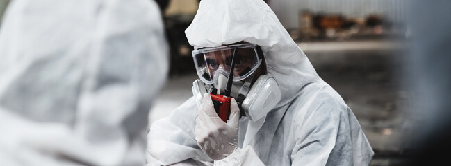 Workers in Protective Suits Checking Chemicals in Old Factory. Protecting Against Hazards and Contamination in Industrial Settings.