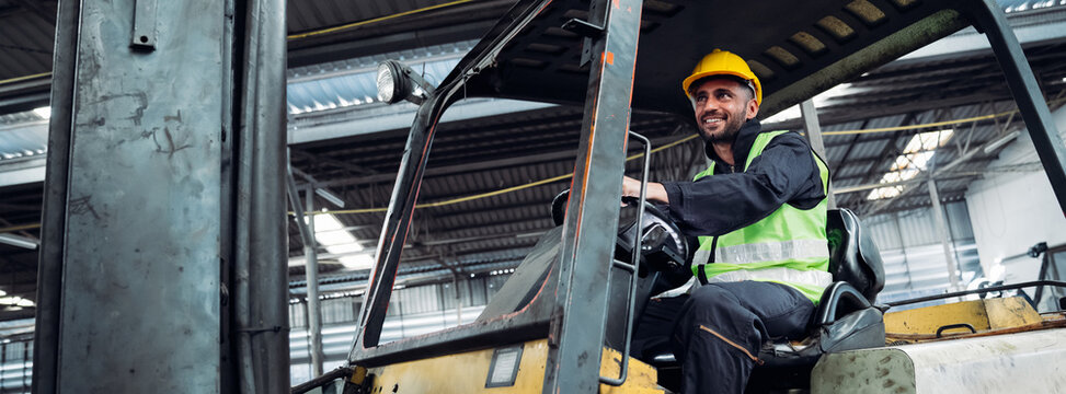 Industrial worker driving a forklift in the factory. Engineer is working and maintaining in the warehouse.
