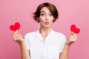Photo of funny good mood girl with bob hair dressed white shirt two hands hold paper hearts pouted...