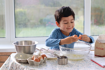 Child broke fresh egg. Child hand crack egg for cooking, baking cake, waffles at home in the...