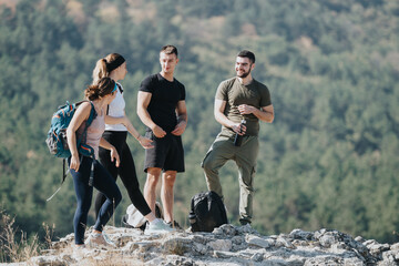 Athletic friends hike through lush forest, enjoy fresh air, nature and each other's company. They wear sportswear and engage in physical activity and discussions in the mountain landscape.