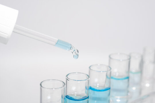 Chemistry laboratory tube glass, science laboratory research and development concept, flask, beaker, and test tubes with dropping blue liquid water sample test, scientific test tubes equipment.