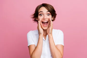 Fotobehang Portrait of funny girl with short hairstyle wear stylish blouse scream in empty space hand on cheek isolated on pink color background © deagreez