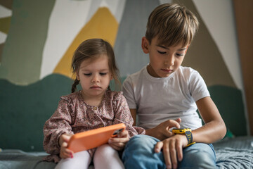 Boy and girl brother and sister use mobile phone smartphone at home