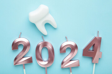 Figure 2024 and tooth with Christmas decoration on blue background.