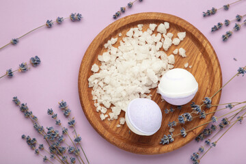 Natural cosmetics. Handmade lavender bath bombs and lavender flowers on wooden board on purple...