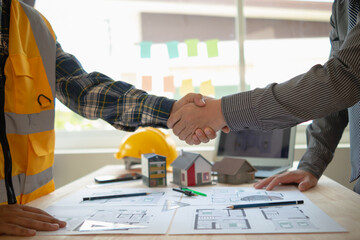 construction engineer joins hands with architect to congratulate housing project that architect...