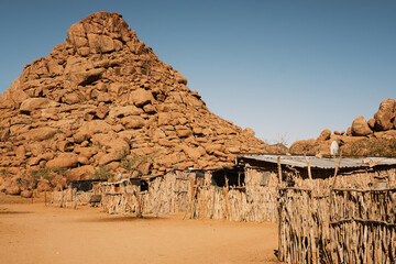 Houses in a Damara tribe village, near Twyfelfontein, Kunene, Namibia. Houses are constructed with tree branches and mud and covered with corrugated metal due to lack of straw.