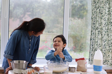 Child and mother making cake. Mixing cake batter in a mixing glass bowl for baking cake waffle pancake. Child holding whisk mixing flour, eggs, milk for pancake day.Family healthy lifestyle concept. - Powered by Adobe