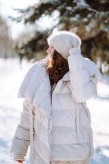 Obraz premium Happy woman walking on a snowy winter day outdoors. Beautiful woman having fun with snow in a snowy park. Walking concept.