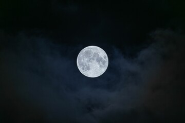 Naklejka na ściany i meble Stunning shot of a full moon in a dark night sky, illuminated against the inky darkness