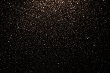 Golden fine abstract bokeh on a black background. Holiday concept, blurred bokeh, overlay for your images. Glitter dust on a black background.