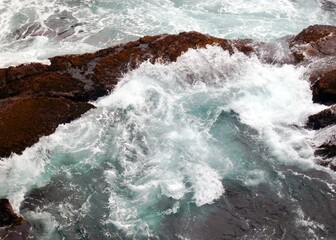 an ocean wave splashing on the rocks in the ocean