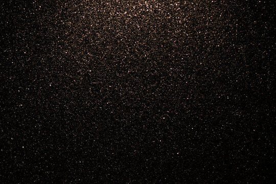 Golden fine abstract bokeh on a black background. Holiday concept, blurred bokeh, overlay for your images. Glitter dust on a black background.