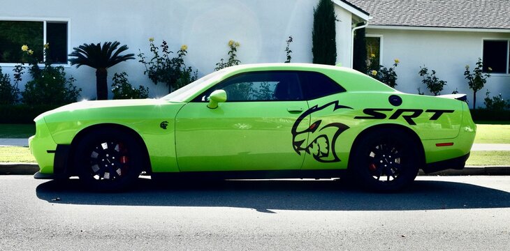 Photo of a bright Neon green SRT Dodge Sports Car parked on street