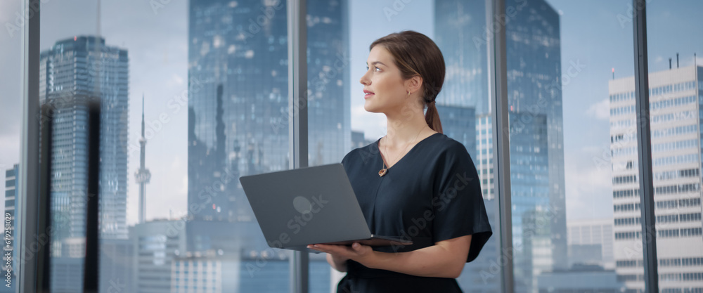 Poster caucasian businesswoman standing in her corner office next to big window with city view and using la