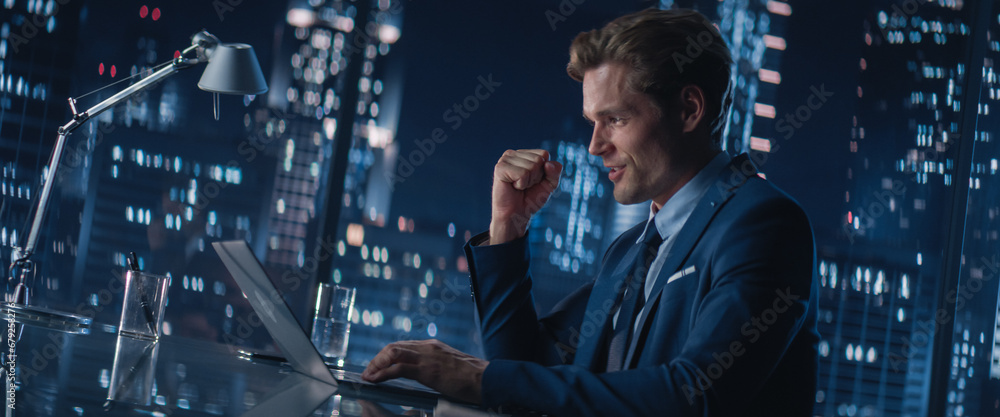 Poster successful handsome businessman working on laptop computer in big city office late in the evening. f
