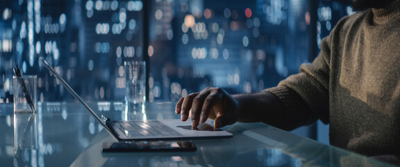 Close Up Of Successful Handsome Black Businessman Working on Laptop in Big City Office Late at Night. African Investment Manager Checking Financial Data from Project Management Report.