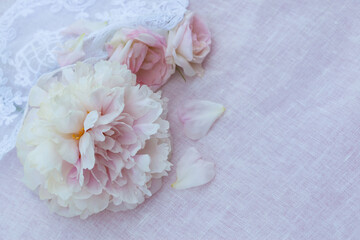 White and pink peony roses on a background of fabric, lace, blur, selective focus. Card for wedding, birthday and Mother's Day.